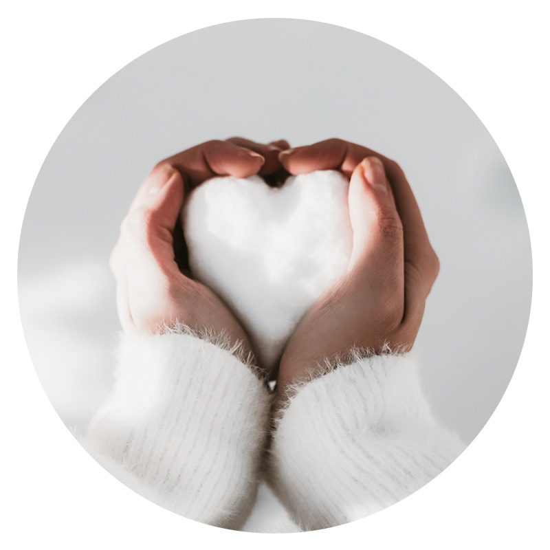 Hands in heart shape holding snow